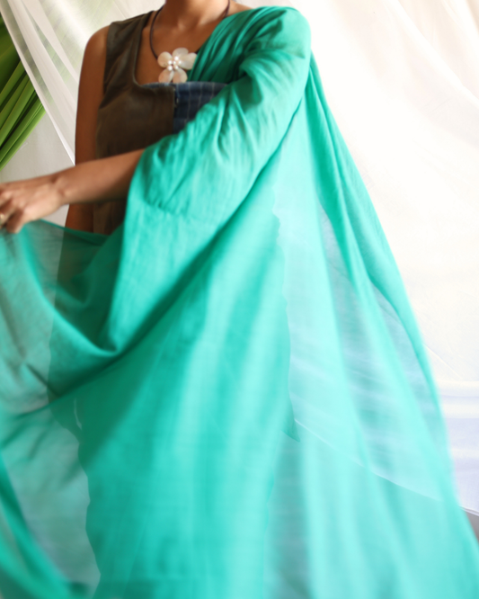 Close-up of the GROVE handwoven Bengal cotton saree in solid green, highlighting its sheer, lightweight texture and natural drape. The breathable fabric showcases traditional handloom craftsmanship refined for modern, everyday wear.