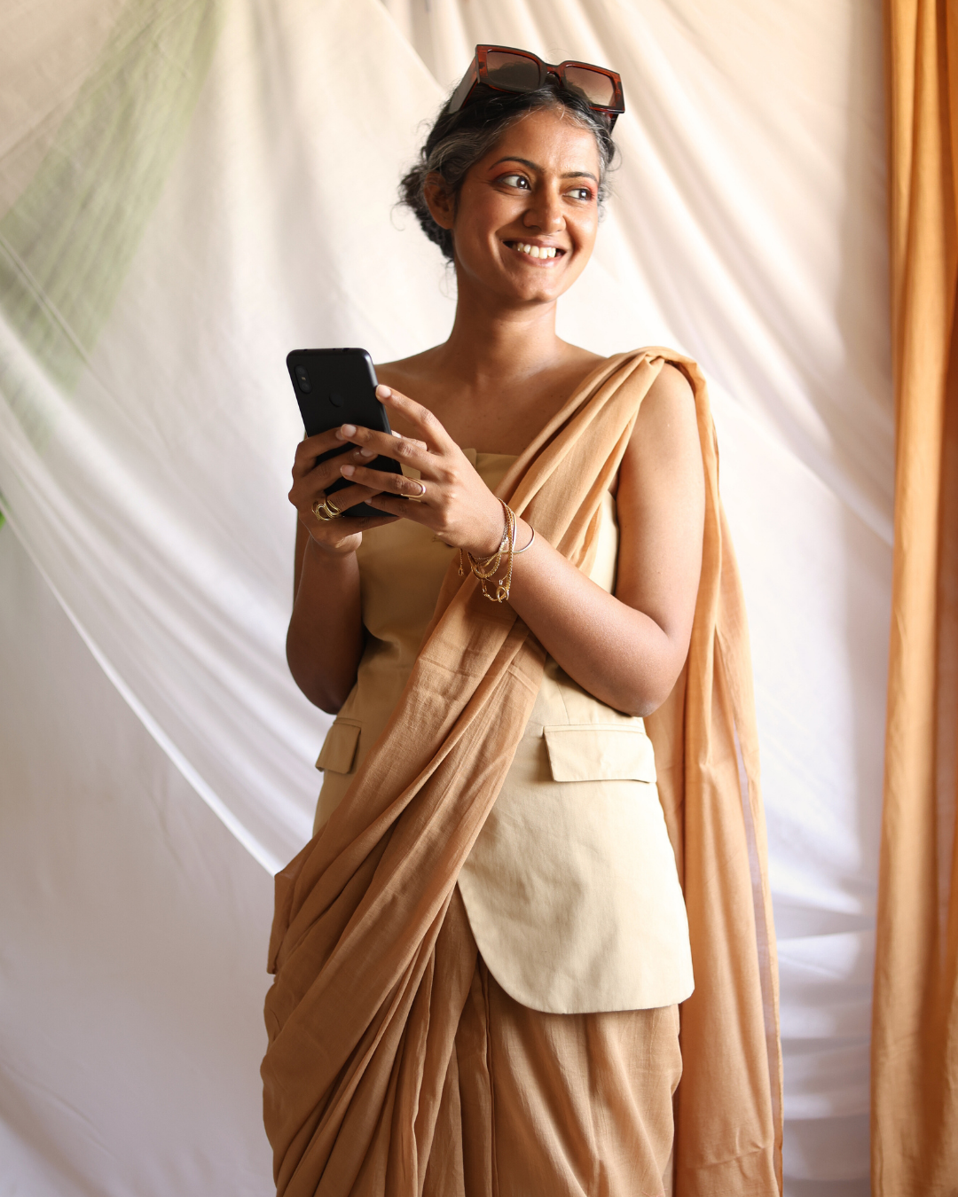 Model wearing the DUNE handwoven earthy beige cotton saree styled with a modern vest, showcasing its soft texture, fluid drape, and lightweight comfort. Crafted by skilled artisans, this solid cotton saree blends traditional weaving techniques with a contemporary silhouette, perfect for versatile, everyday elegance.