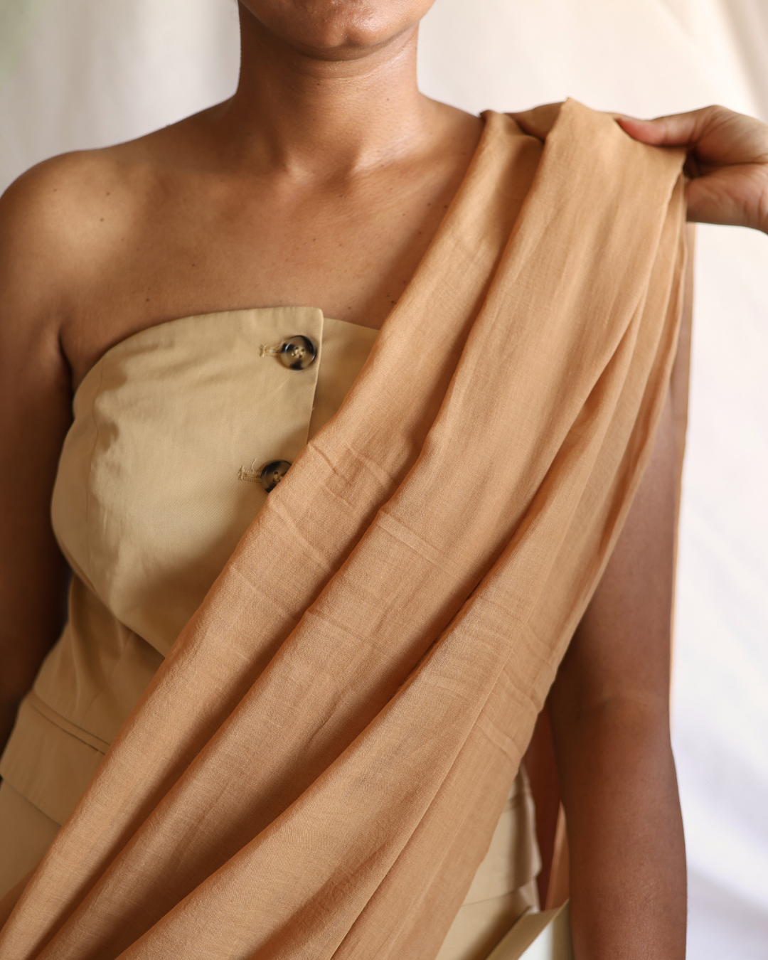 Close-up view of the DUNE handwoven cotton saree draped elegantly over the shoulder, showcasing its soft, earthy desert-sand hue and natural texture. The subtle weave and timeless neutral tone reflect the calm, flowing beauty of shifting dunes — a versatile saree perfect for minimal, contemporary styling.
