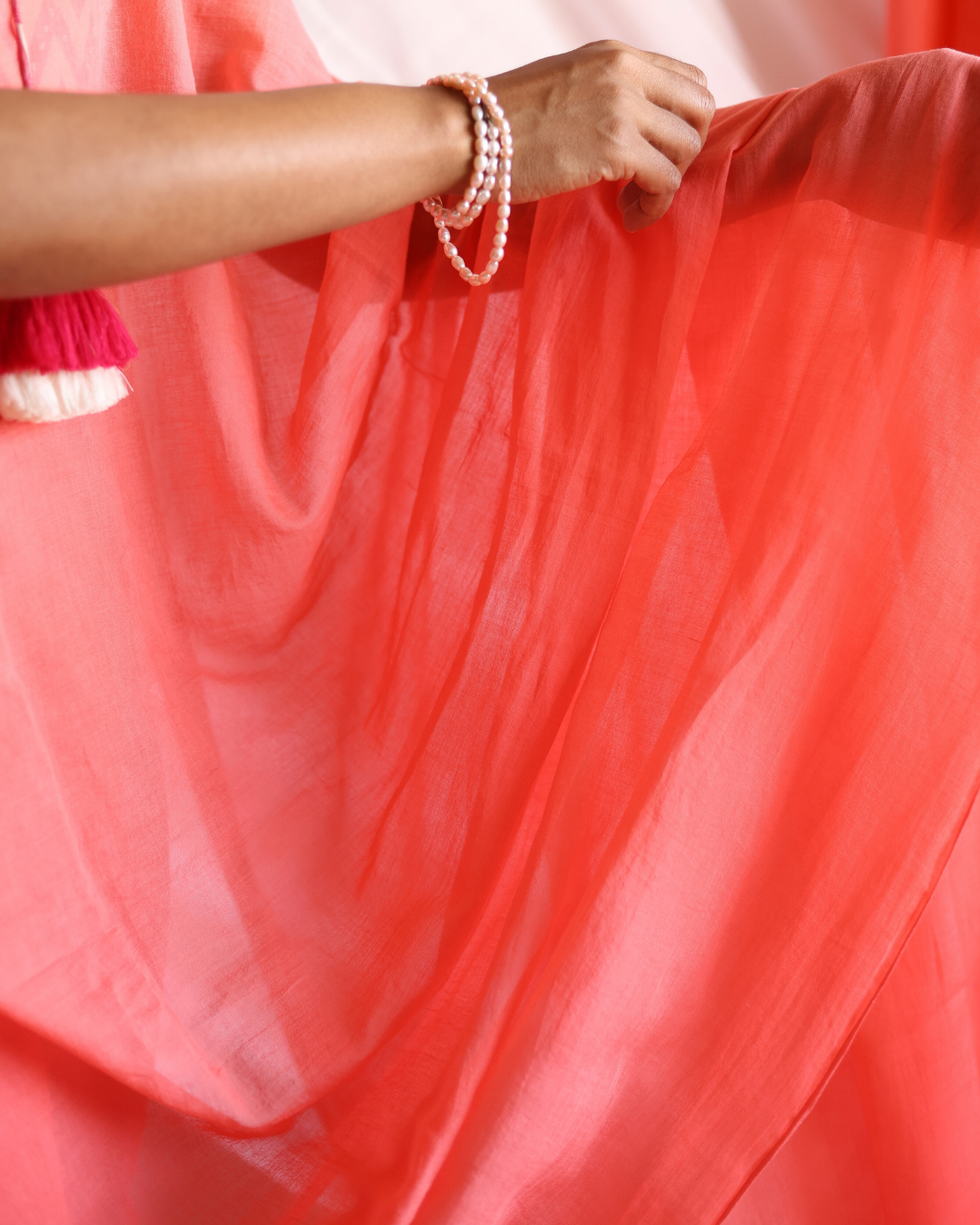 Close-up of the Dawn soft coral saree, showing its airy handwoven texture and gentle drape. The lightweight fabric captures morning light beautifully, highlighting the saree’s smooth flow and solid colour — perfect for minimalist, everyday elegance.