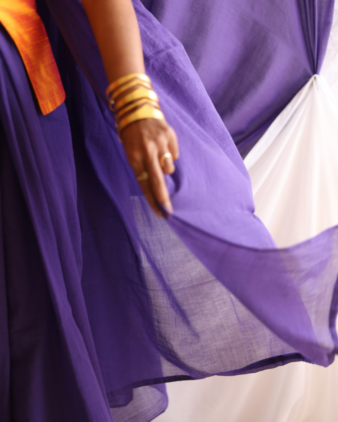 A close-up of the Galaxy solid purple handloom cotton saree in motion, showcasing its soft, sheer drape and lightweight texture. This handcrafted saree blends traditional weaving with timeless minimalism, offering versatile elegance for everyday wear and special occasions.