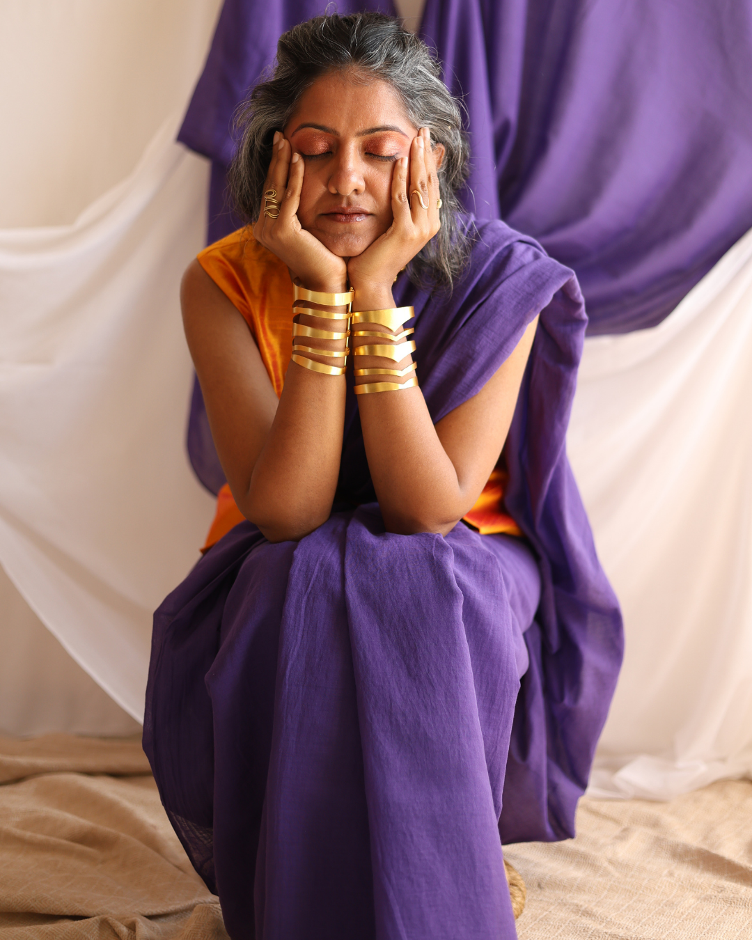 A woman draped in the GALAXY solid purple handloom saree, styled with bold gold jewellery. This handcrafted cotton saree blends simplicity with statement elegance, celebrating slow fashion and artisan craft.