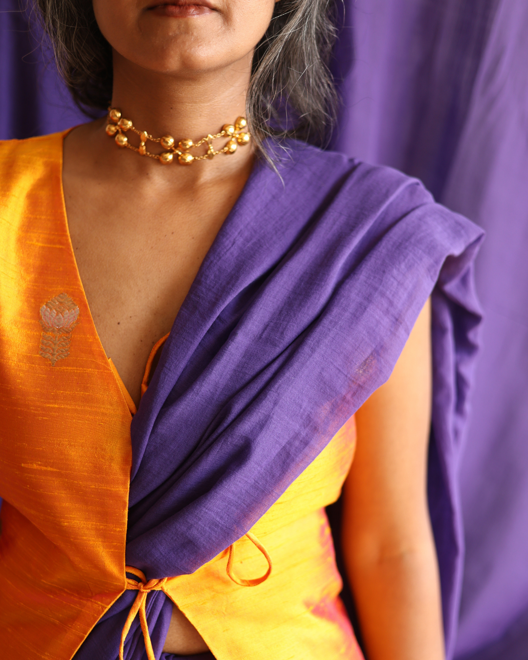 Close-up of the Galaxy solid purple handloom saree draped over a golden blouse, showcasing the rich texture and soft drape of artisan-made cotton. This handcrafted saree blends traditional weaving with a modern minimalist style, perfect for timeless, everyday elegance.