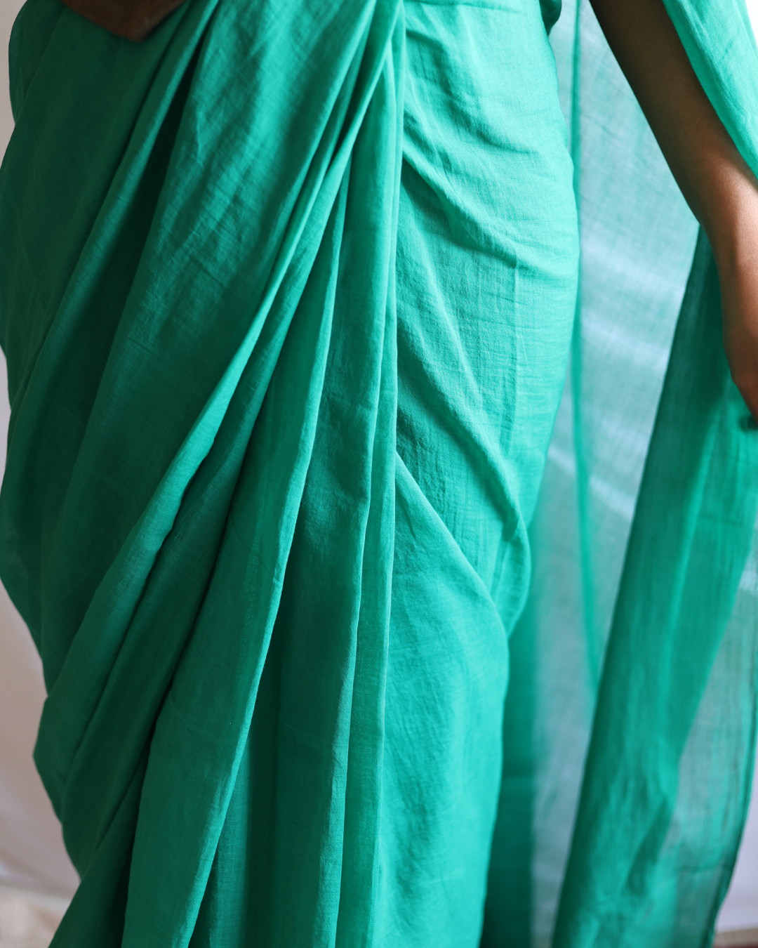 Close-up of the GROVE artisan-made solid green cotton saree, featuring fine pleating and soft texture. Handwoven with care, it blends traditional craftsmanship with modern minimalism.