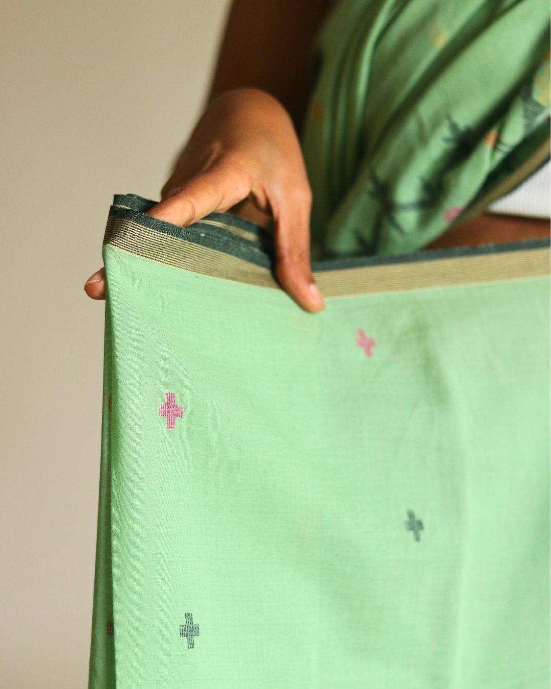 Close-up of a light green handwoven Bengal cotton saree showcasing its subtle woven motifs and finely finished border. This image highlights the precision of traditional handloom weaving and the breathable, lightweight texture that makes the saree ideal for everyday elegance and timeless style.