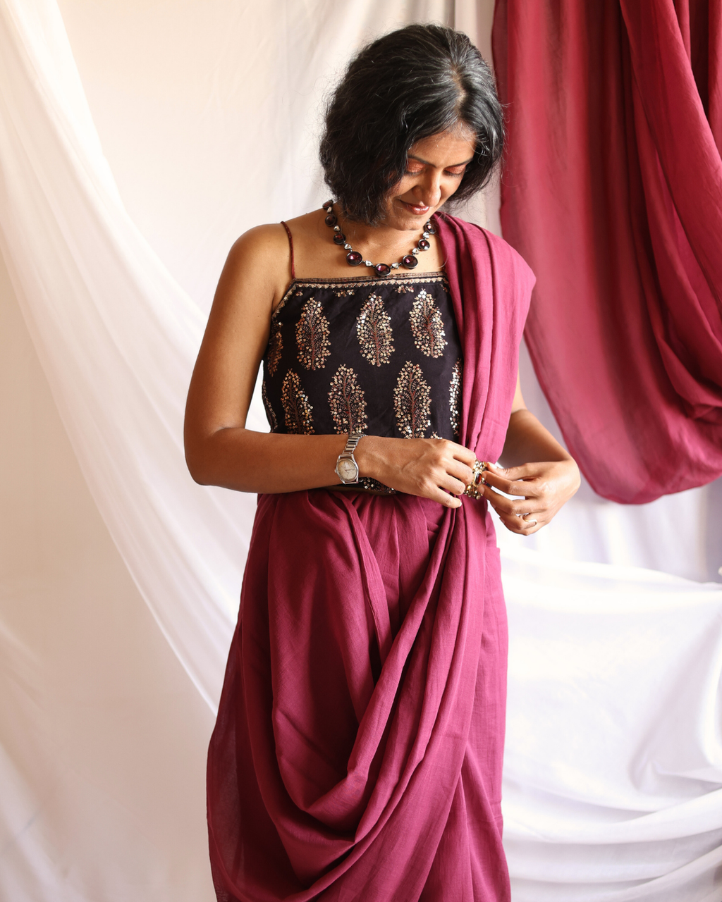A woman wearing the POMEGRANATE pure Bengal cotton red saree, handwoven by artisans and styled effortlessly for everyday elegance. The lightweight, breathable fabric drapes beautifully, showcasing the saree’s deep pomegranate hue and soft texture — perfect for workdays, festive occasions, or slow living wardrobes.
