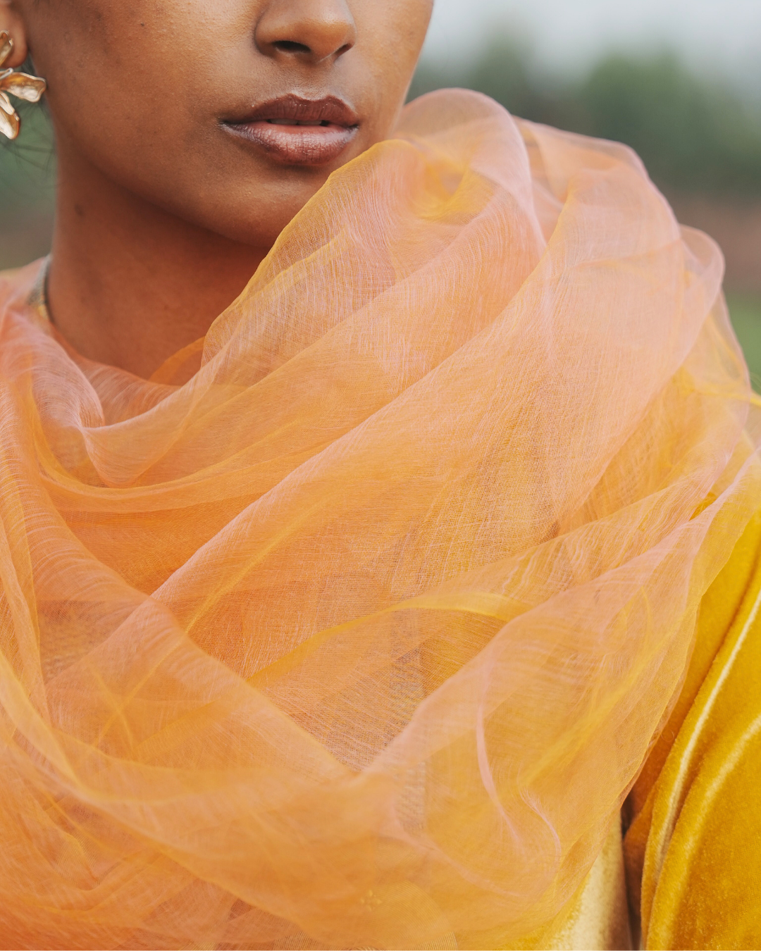Close-up of the Sunburst Pink handwoven silk scarf, highlighting its soft, weightless texture and subtle golden-pink hues. Crafted by skilled artisans using traditional handloom techniques, this luxury silk scarf is designed to drape effortlessly, adding timeless elegance to any outfit.