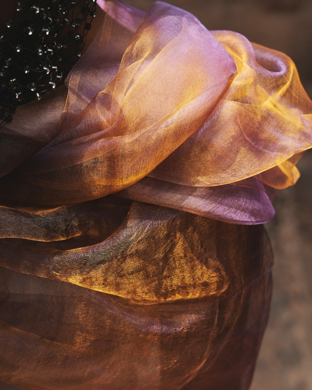 Close-up of the Sunburst Purple handwoven dual-tone pure silk scarf, showcasing its featherlight texture and shifting hues of gold and blush. Crafted in Phulia, West Bengal, this artisan stole embodies slow fashion and traditional Indian weaving in a luxurious, ethereal drape.