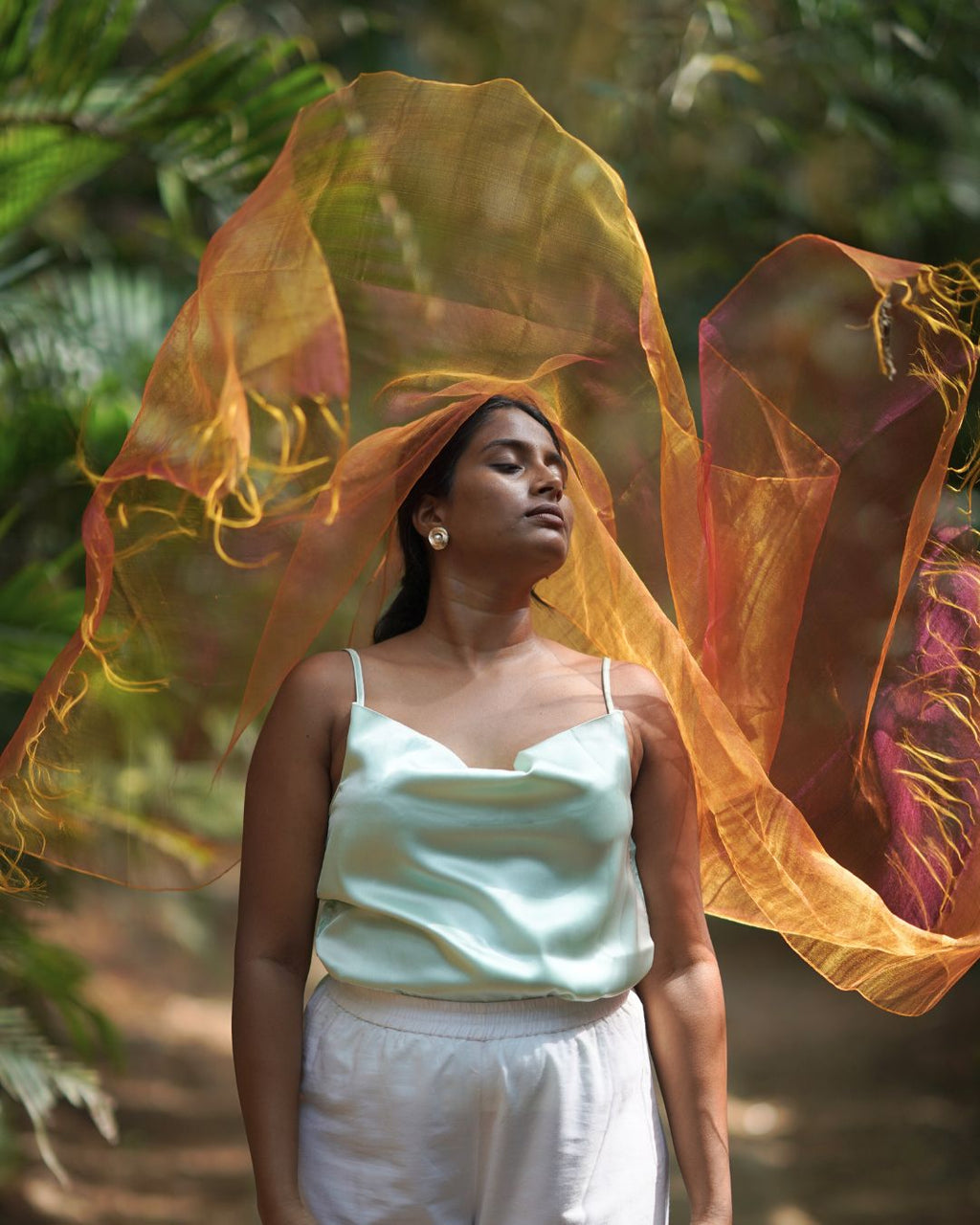 Woman with a flowing orange scarf against a natural background
