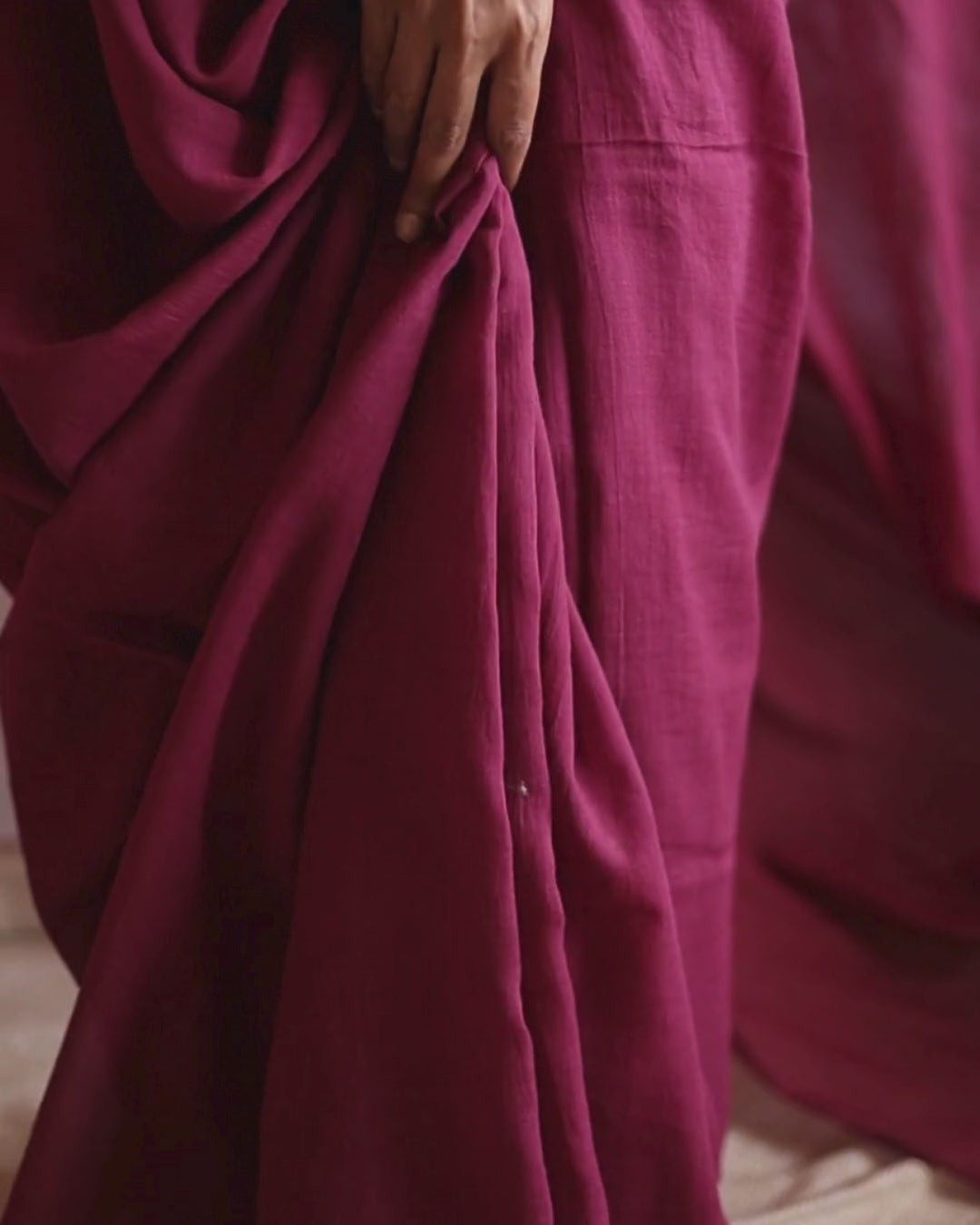 Close-up video of the POMEGRANATE pure Bengal cotton red saree, showing the soft pleats and natural drape in motion. The deep crimson fabric flows gracefully, highlighting its lightweight, handwoven texture and artisanal craftsmanship.